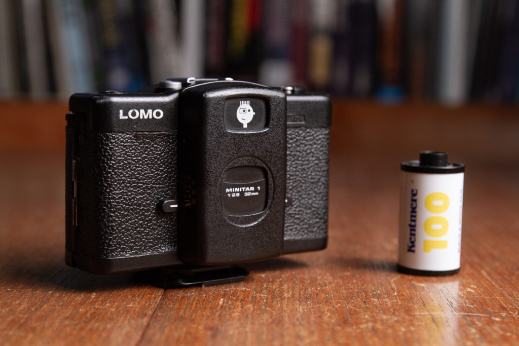 Color image of LOMO LC-A camera beside a roll of Kentmere 100 ASA 35mm film.